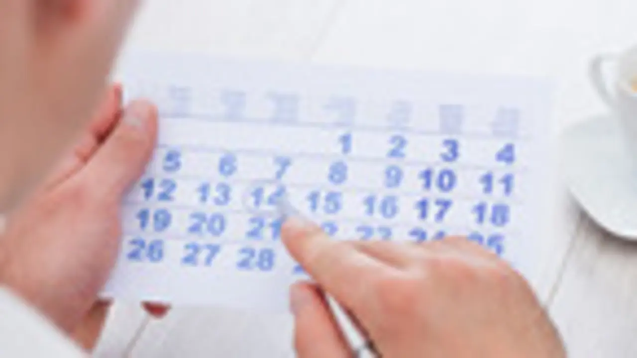 Close-up Of Man Marking With Pen And Looking At Date On Calendar